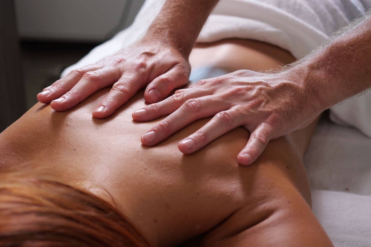 Mani che scorrono lente sulla schiena durante un massaggio relax